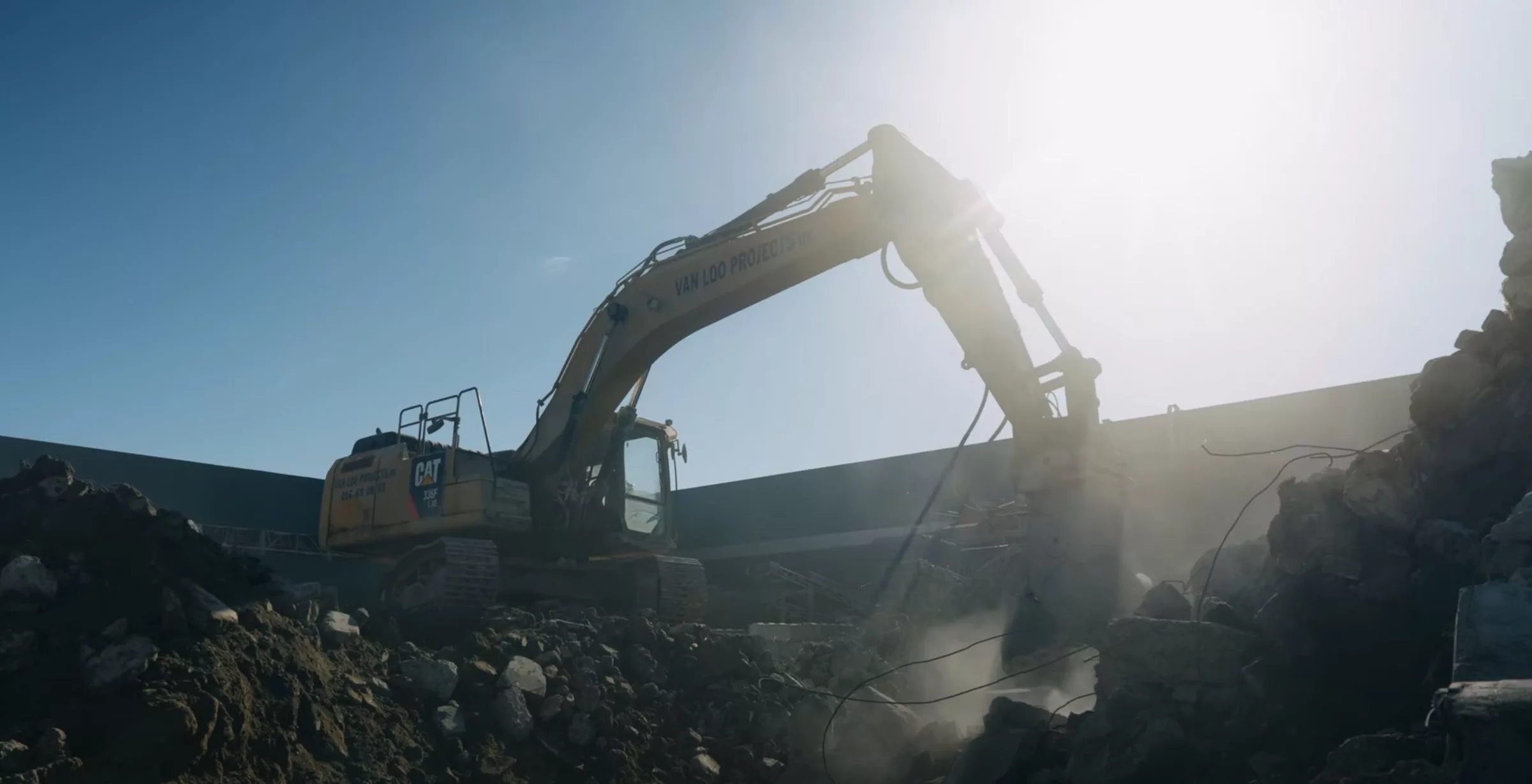 Graafmachine in werking op afbraaksite bij heldere zon